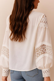 Back view of the white blouse with solid back panel, lace bands on the sleeves and a clean straight hem.