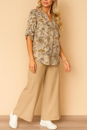 Front three-quarter view of the apricot floral split V-neck blouse paired with beige wide-leg pants; relaxed, above-ankle length.