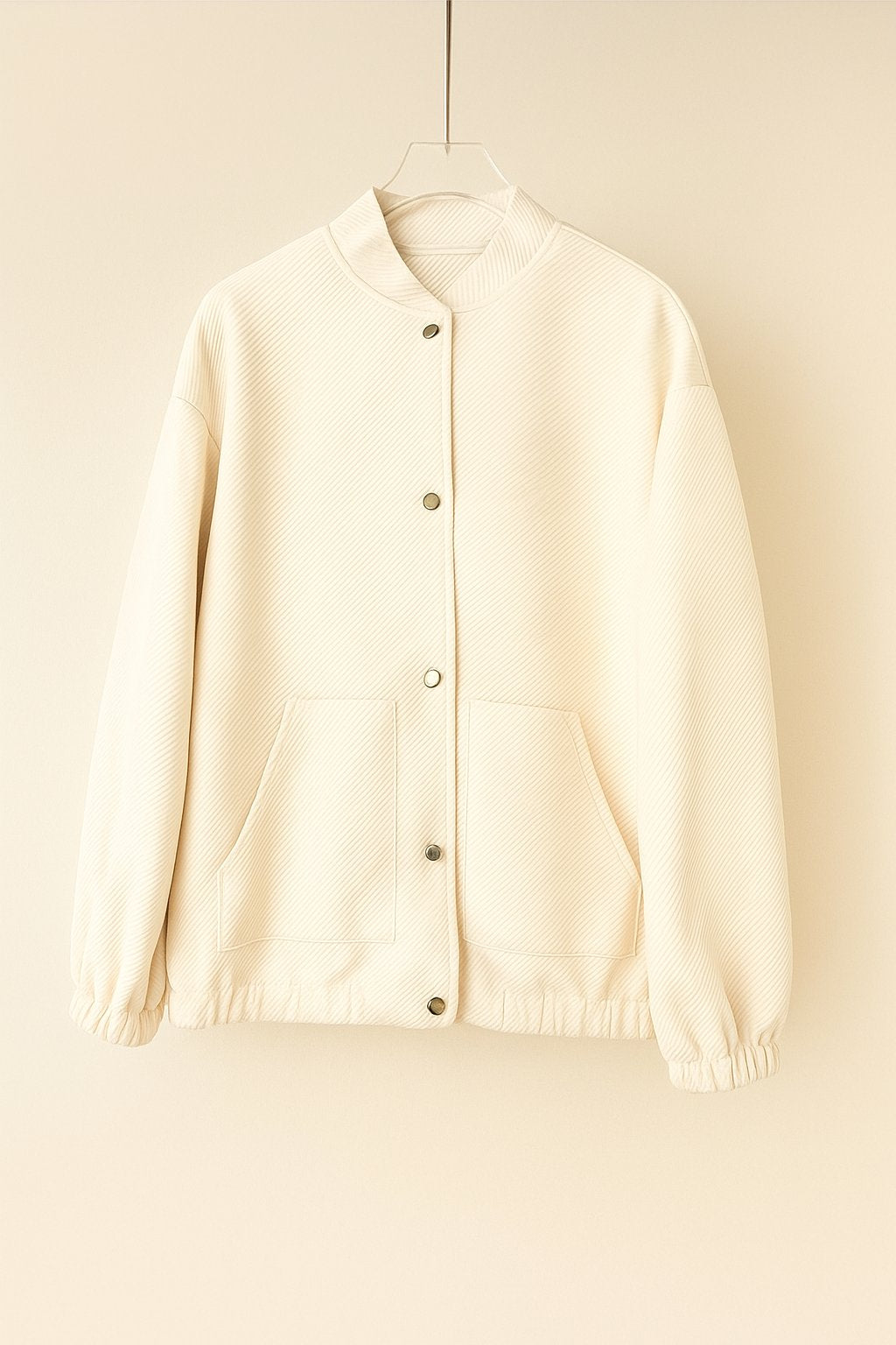 Hanger flatlay, front view of the apricot textured snap-button bomber jacket with rib-knit collar, patch pockets, elastic cuffs and hem.