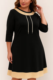 Centered front view of the black contrast-trim A-line dress; drawstring neckline and three-quarter sleeves visible.
