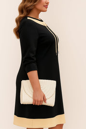 Left side view of the black contrast-trim A-line dress highlighting the drawstring neckline, smooth drape and above-knee hem.
