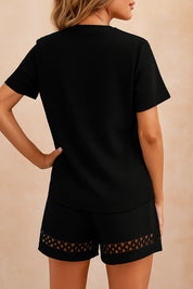 Back view of the black eyelet-trim V-neck top and shorts set showing the straight back hem and textured knit