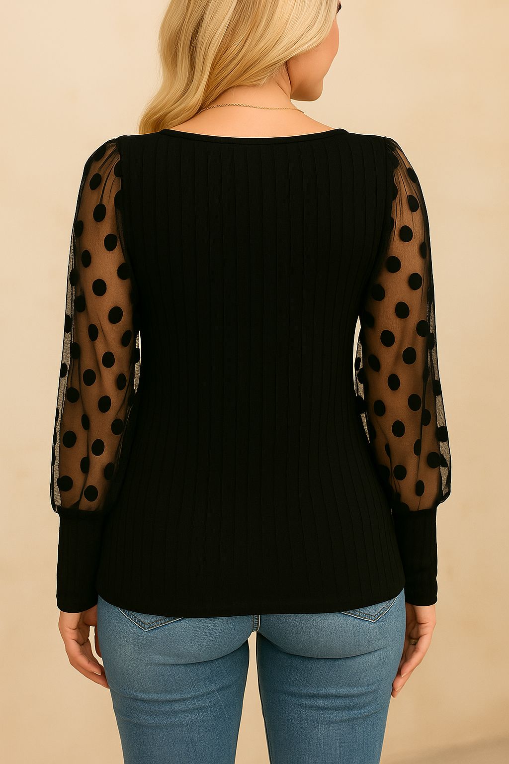 Black blouse showing polka-dot mesh sleeve fabric and rib-knit body texture — front detail close-up view