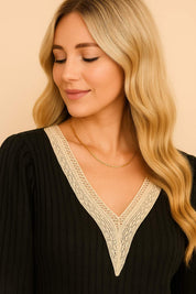 Neckline detail view of the black ribbed blouse showing the V-neck shape and beige crochet edging.