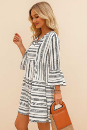 Black-and-white boho-print tie-neck mini dress with flounce three-quarter sleeves and tiered silhouette — left side view.
