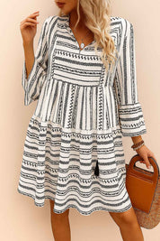 Black-and-white boho-print tie-neck mini dress with three-quarter sleeves and tiered skirt, lightweight drape — relaxed front view