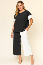 Front view of a women’s black and white colorblock textured short-sleeve top with matching wide-leg pants on an elastic waist
