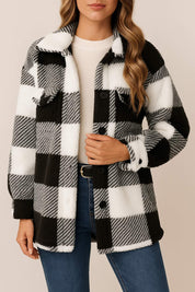 Straight front view of the black-and-white fuzzy plaid button-up jacket; shirt collar, button front and flap chest pockets are visible.