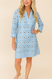 Front view of a woman in a blue printed tunic dress with striped trim on collar, cuffs, and hem, featuring 3/4 sleeves and a relaxed fit