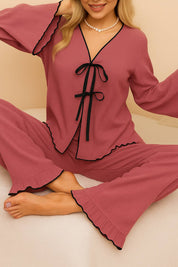Relaxed cross-legged pose in blush ruffle sleepwear set – close-up of fabric and bow