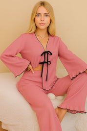 Soft pink lounge set with black contrast detail – model sitting, looking ahead
