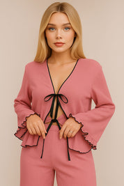 Blush pink ruffle lounge set with contrast trim – front view sitting on bed