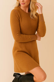 Close three-quarter front view of a women’s knit sweater dress in camel brown with a crew neckline, long sleeves and ribbed cuffs; clean center seam and a soft A-line hem for smooth drape.