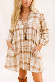 Woman wearing a beige and camel plaid babydoll mini dress with long sleeves and side pockets – casual fall outfit with relaxed fit
