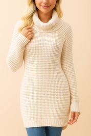 Front view of a women’s turtleneck waffle-knit tunic sweater in cream with long sleeves, ribbed cuffs and hem, and subtle side slits.