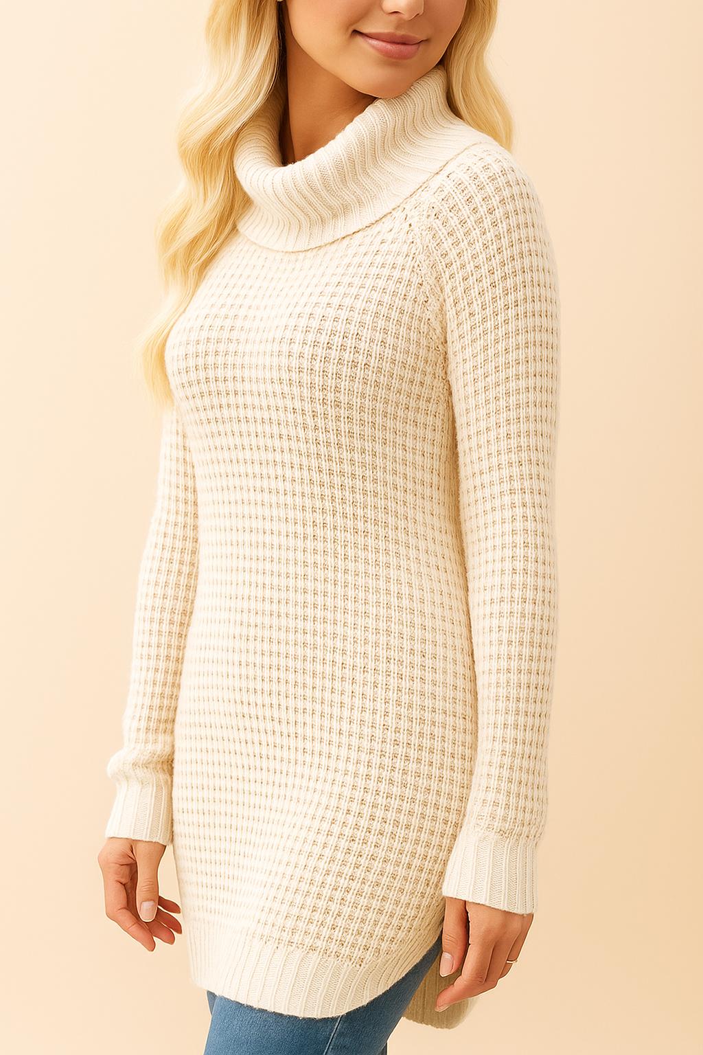 Left side view of the cream waffle-knit turtleneck sweater showing the tunic length, curved high-low hem and small side slit.