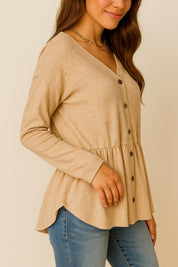 Left three-quarter view of the dust-storm beige V-neck button-front long-sleeve top showing the drop-shoulder cut and curved hem.