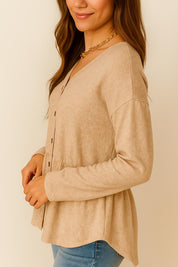 Right three-quarter view of the dust-storm beige V-neck button-front top with relaxed sleeves and rounded hemline.