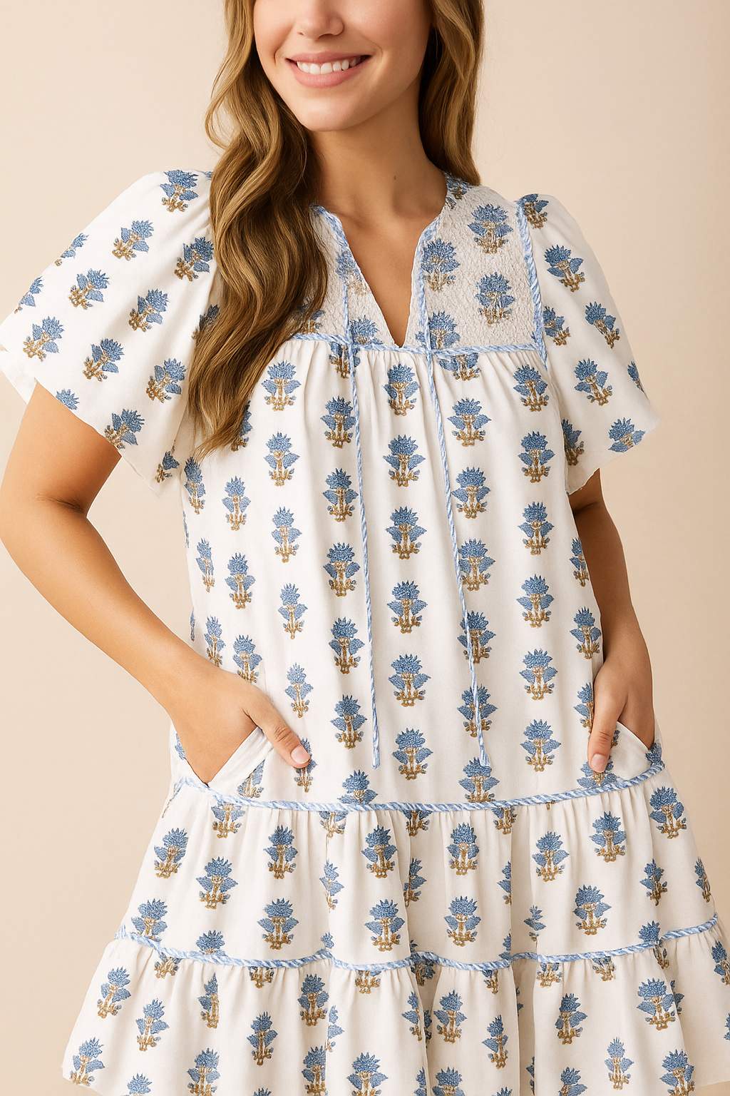 Dusty-blue floral-embroidered cotton babydoll mini dress showing V-split neckline panel and yoke stitching — front detail view.