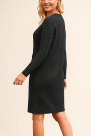 Woman wearing a black sweater dress against a beige background