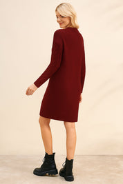 Woman wearing a burgundy sweater dress with black boots on a beige background