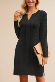 Woman wearing a black cable knit dress with a beige clutch against a beige background