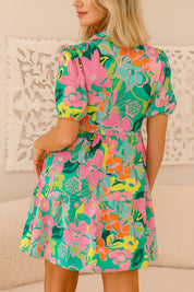 Floral button-down babydoll dress in green multi with puff sleeves and tiered mini skirt — back view.