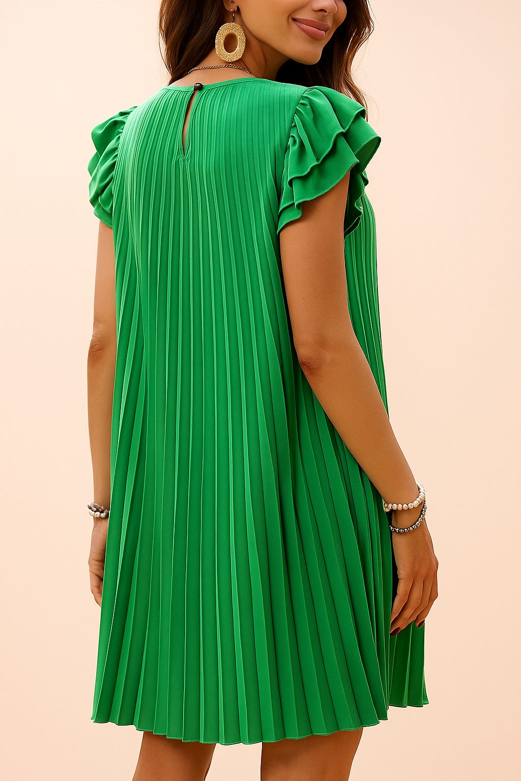 Back view of a green pleated mini dress with ruffle sleeves and keyhole button closure, accessorized with bold earrings and pearl bracelets — elegant summer detail shot.