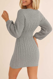 Back view of the cable-knit sweater dress in heather gray with a ribbed waistband, full cable pattern and a clean mini-length hem.