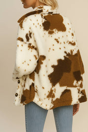 Back view of the ivory and brown cow-print fuzzy jacket showing the pattern distribution and rounded hem.