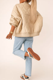 Back view of the ivory quilted bomber jacket highlighting the ribbed waistband and allover wave quilting in a relaxed bomber fit.