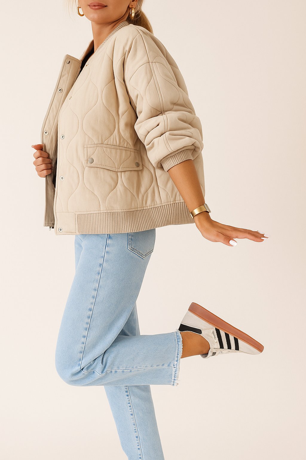Left side view of the ivory quilted bomber jacket with rib-knit collar and cuffs, wave quilting and snap-flap pocket.