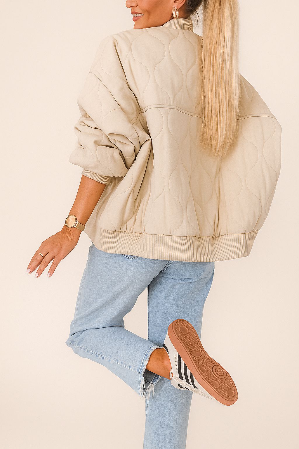 Back view of the ivory quilted bomber jacket featuring wave quilting across the back and rib-knit hem and cuffs