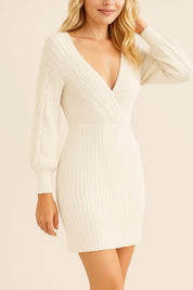 Three-quarter view of the wrap sweater dress in ivory with cable-knit balloon sleeves, a deep V neck and elongating vertical ribs.