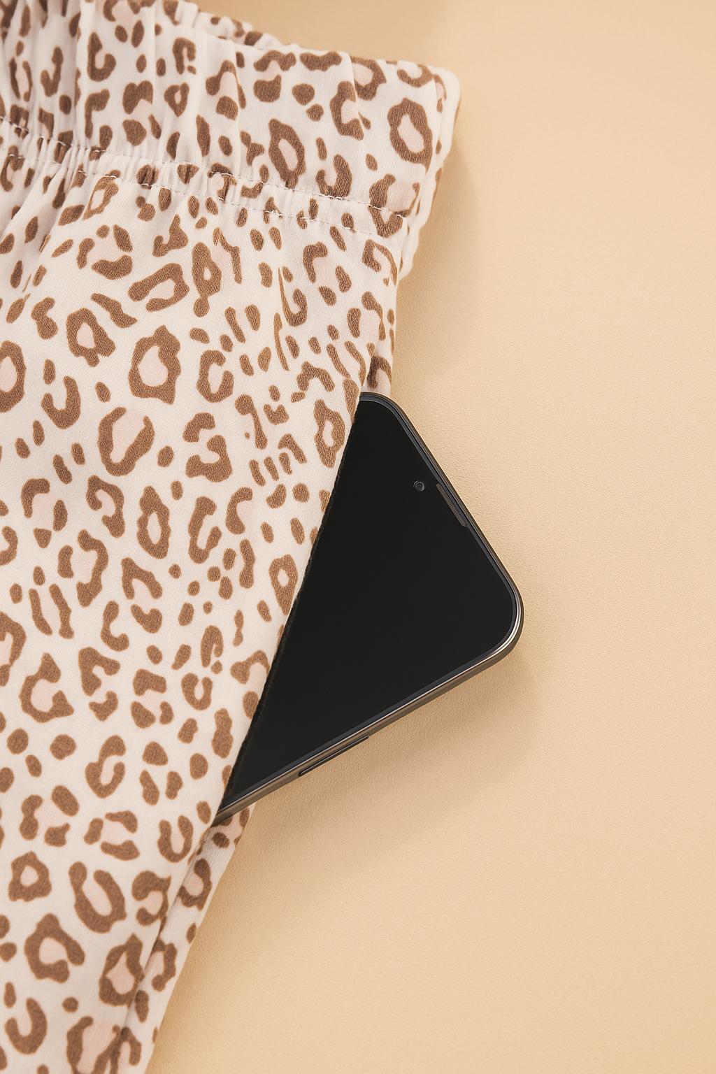 Close-up of leopard print pajama pants showing functional side pocket with smartphone, soft stretchy fabric