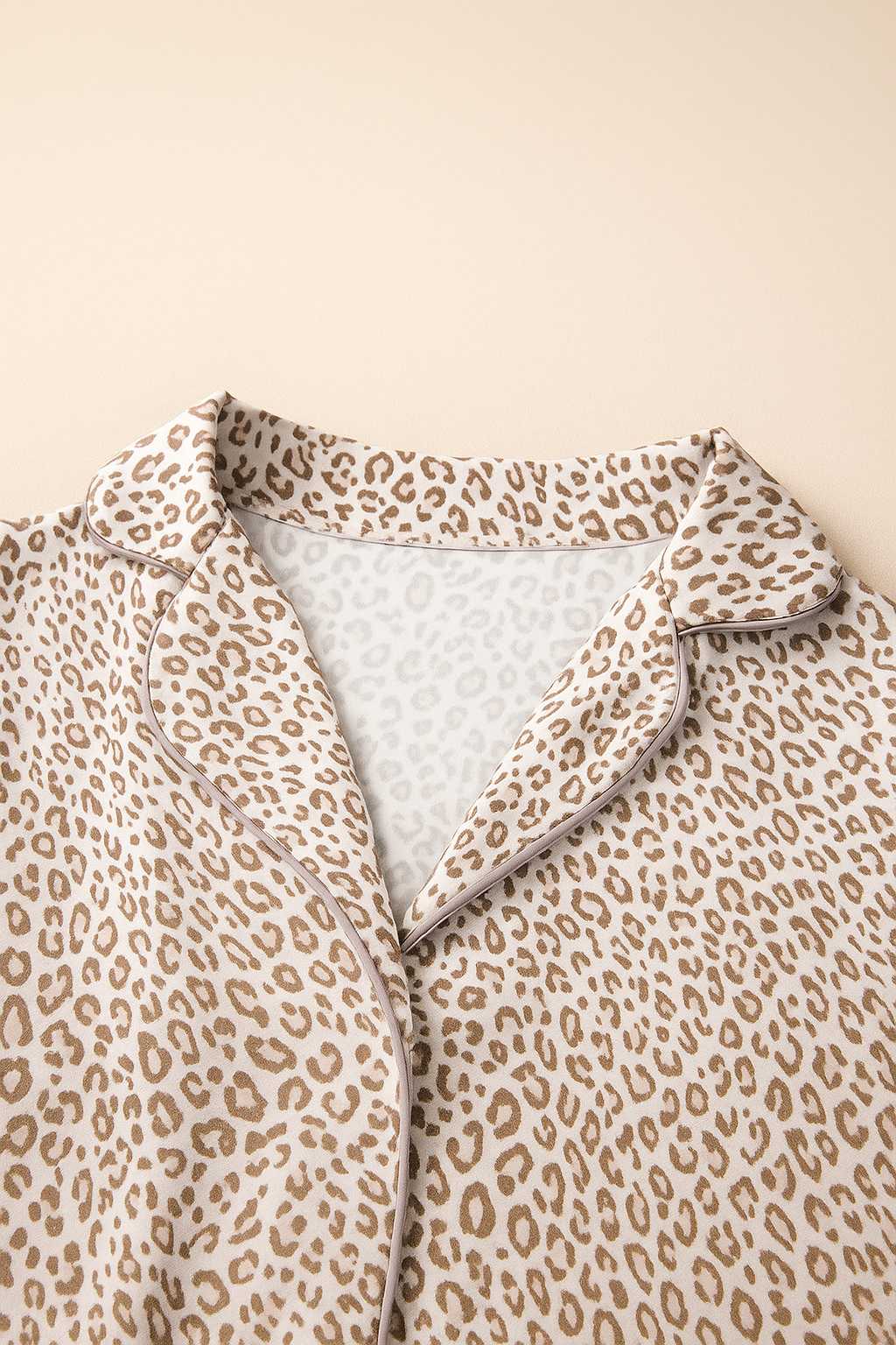 Close-up of leopard print pajama top showing notched lapel collar with contrast piping and soft knit fabric texture