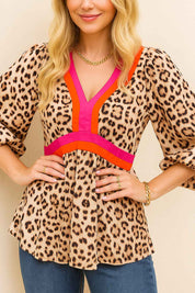 Close front detail of a women’s leopard-print V-neck blouse with colorblock trim at the neckline and waist and soft balloon sleeves with elastic cuffs