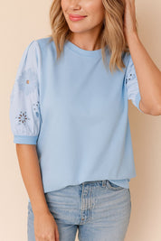 Front view of the light blue puff-sleeve blouse showing the sleeve floral eyelet cutwork and a straight hem