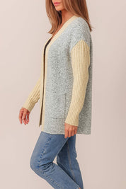 Left side view of the light-gray and pastel-yellow colorblock open-front cardigan showing the patch pocket opening, ribbed cuffs and straight hem.