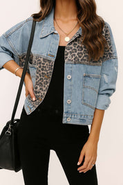 Front view of the light-wash denim jacket showing the leopard-panel yoke, button placket, relaxed drop-shoulder and slant pockets.