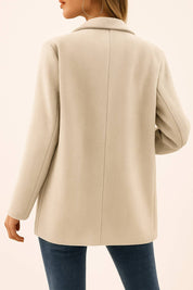 Back view of the oatmeal beige herringbone double-breasted coat with a clean back panel, center seam and straight hem