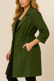 Left side view of the olive green plus-size lapel trench coat with roll-tab sleeve, drawstring waist and slant welt pocket opening.