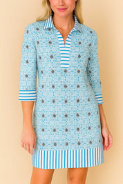 Pastel-blue floral tunic dress showing striped collar edge and placket finish, lightweight woven texture — front detail view.