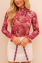 Close front detail view of a women’s pink floral mock-neck long-sleeve blouse with flounce cuffs