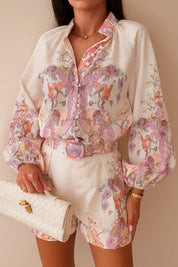 Front detail view of the pink floral blouse showing the button placket and patterned belt on the matching shorts.