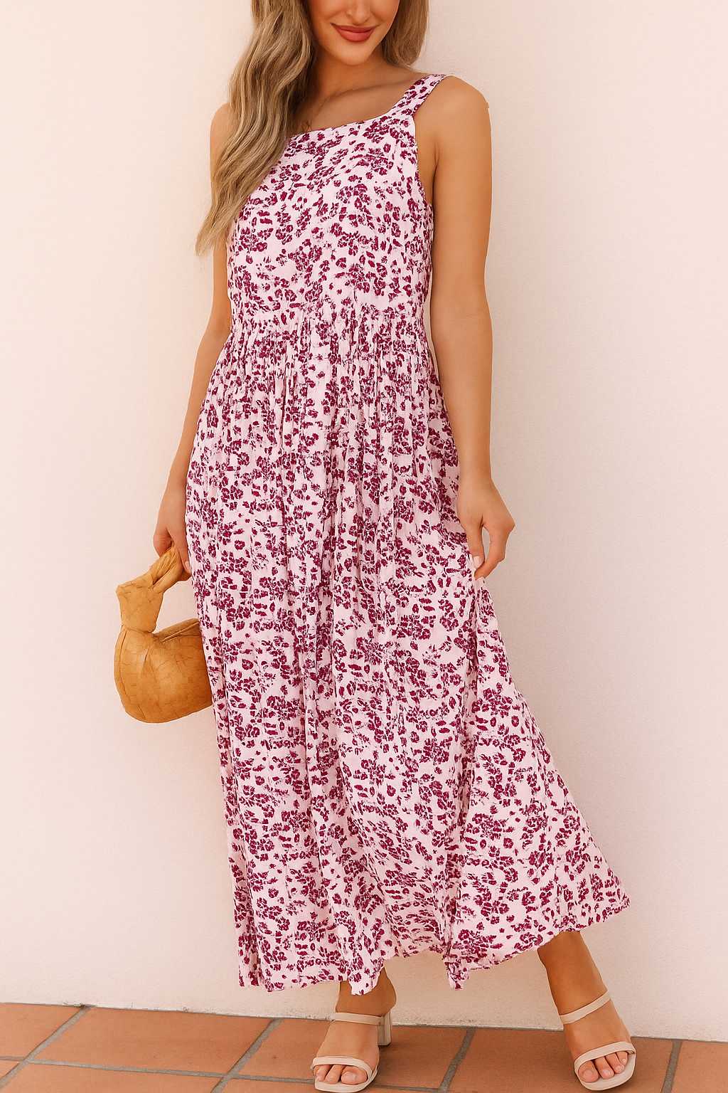 Pink-floral square-neck sleeveless maxi dress with relaxed drape, styled with round woven bag — front view