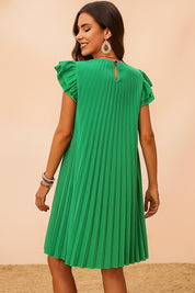 Back view of a woman turning in a green pleated mini dress with ruffle sleeves and teardrop earrings, showing flowy swing movement and summer charm.