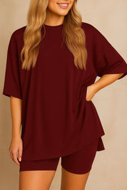 Plus size woman wearing an oversized burgundy lounge set with round neck top and matching shorts