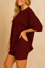 Side view of plus size woman wearing an oversized burgundy lounge set with relaxed fit top and matching shorts