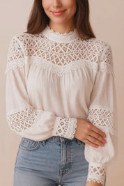 Short lookbook video of a white lace-yoke high-neck long-sleeve blouse with crochet trim and sheer lace inserts on the sleeves, shown in studio lighting